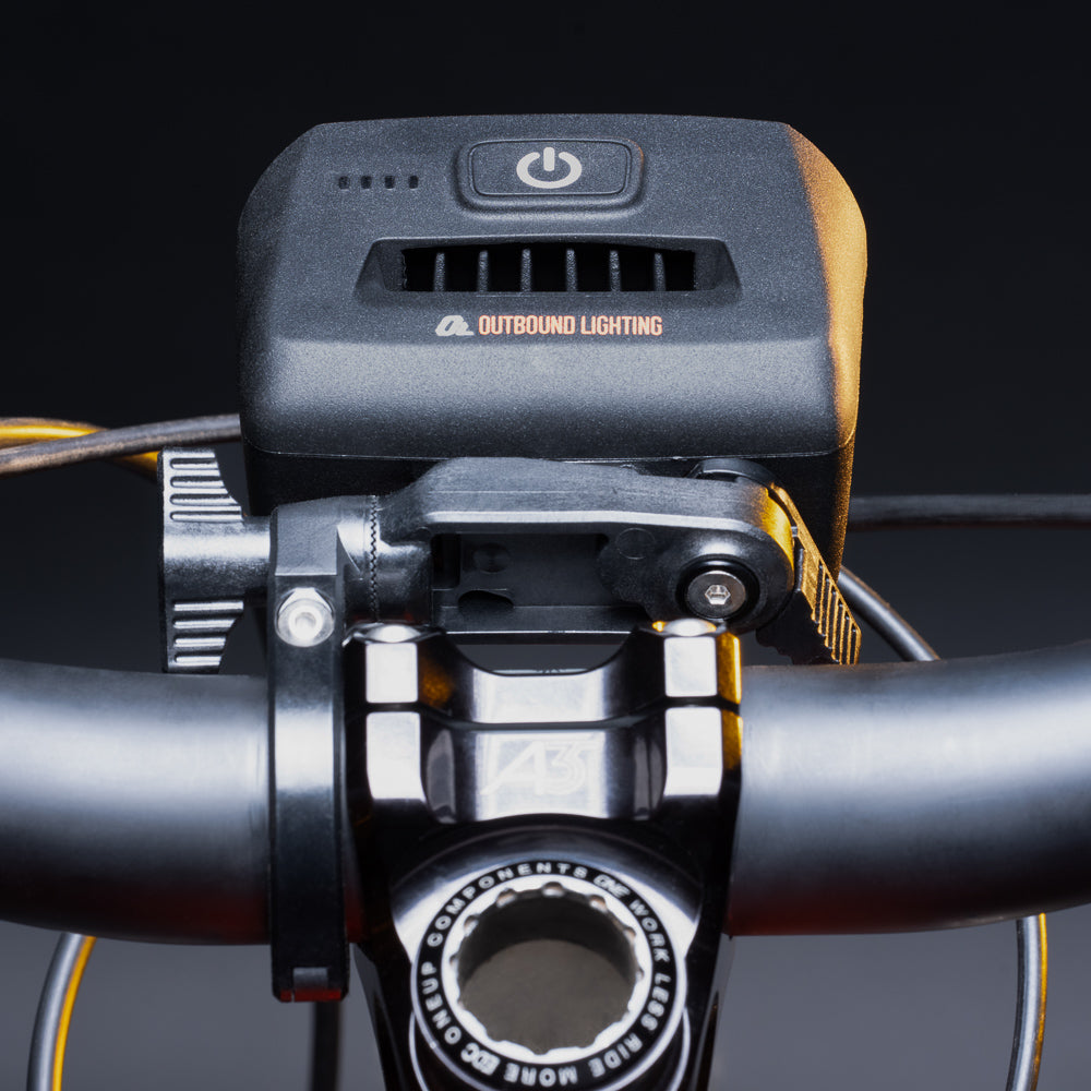 Bike light on the quick release handlebar mount clamped beside the stem, rider's view
